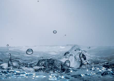 Nahaufnahme von klarem Wasser, das spritzt, wobei die Tröpfchen in der Luft schweben und ein Gefühl von Frische und Reinheit vermitteln.